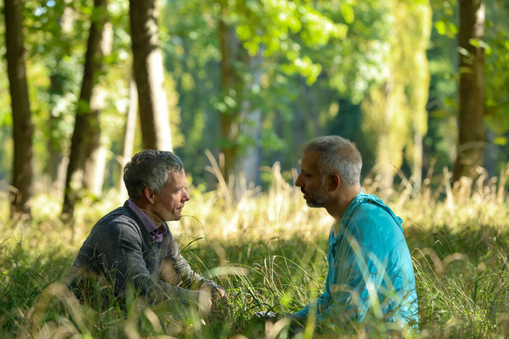 Die zwei Seminarleiter sitzen in einer Waldlichtung im Grünen.